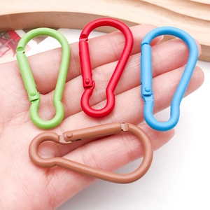 Macro shot of colorful aluminum gourd carabiners in hand showing size and spring gate detail