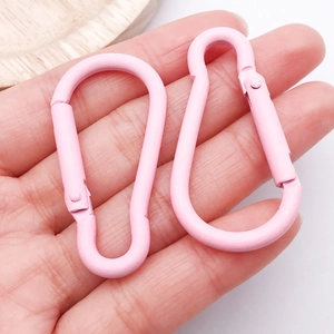 Detail showing two pink gourd-shaped carabiner clips with matte finish held in hand