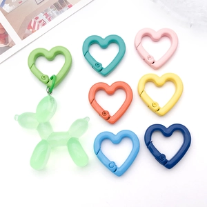 Close-up of heart-shaped alloy spring clasps in assorted matte colors and a balloon dog pendant