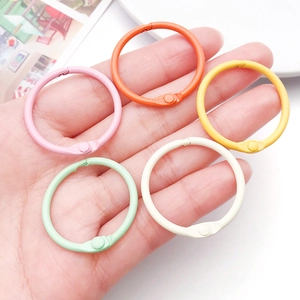 Close-up of hand holding five colorful 30mm metal loose-leaf binder rings in pastel colors