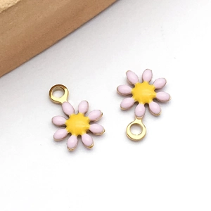 Makro-Detail von rosa und gelben Gänseblümchen-Anhängern mit vergoldeten DIY-Ösen