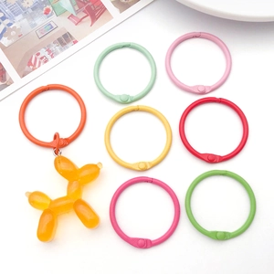 Colorful 30mm binding rings with yellow resin balloon dog charm on a white background