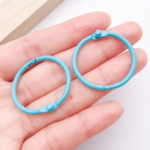Detail showing two light blue matte finish metal binder rings held by hand for DIY crafts