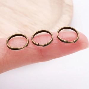 Makroaufnahme kleiner Bronze-Doppelspaltringe für DIY-Schmuck auf einer Fingerspitze