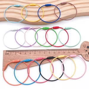 Portachiavi colorati in cavo d'acciaio con chiusura a vite su un righello di legno