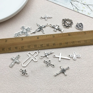 Vue détaillée de pendentifs cœur et croix en argent antique avec une règle en bois pour l'échelle