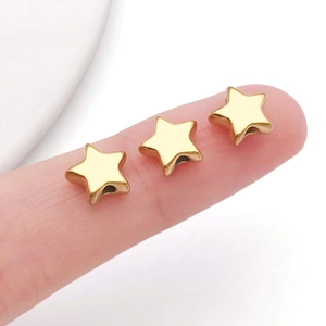 Macro shot of three small gold star-shaped beads with side holes for DIY jewelry making