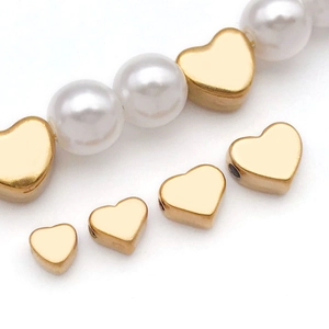Macro detail of golden heart-shaped metal spacer beads and white pearls for DIY jewelry