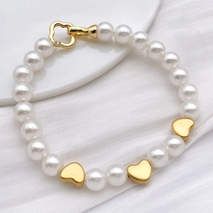 Pearls bracelet with gold heart spacers and heart-shaped clasp on white silk fabric