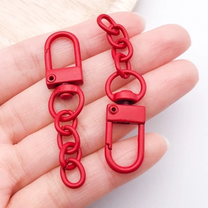 Detail of matte red alloy lobster clasp with chain held to show scale and texture