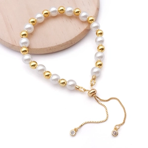 Elegantes Perlenarmband mit goldfarbenen Perlen und verstellbarem Zugverschluss auf Holz