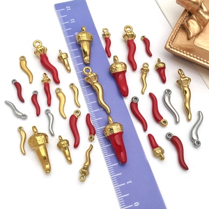 Various sizes of stainless steel chili pepper pendants in gold, silver, and red enamel