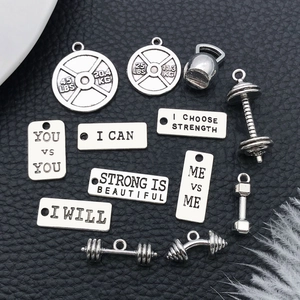 Macro shot of silver fitness charms featuring dumbbells and kettlebells on black leather