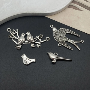 Detailed antique silver bird charms showing intricate feather textures and vintage finish