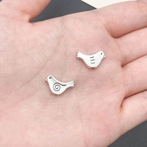 Detailed view of two small bird-shaped antique silver alloy beads for DIY jewelry making