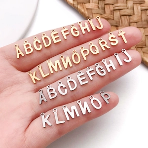 Gold and silver stainless steel small letter charms for DIY jewelry on white background