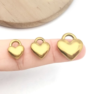 Comparaison de trois tailles de pendentifs coeur dorés sur doigts pour création de bijoux
