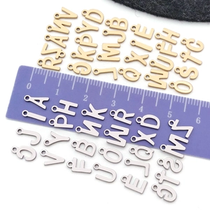 Detailed macro view showing gold and silver alphabet charms with size measurement scale