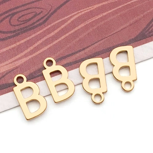 Four golden metal lowercase letter B charms for DIY jewelry making on wood background