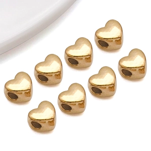 Dettaglio di perline distanziatrici a cuore dorato lucido per la creazione di braccialetti