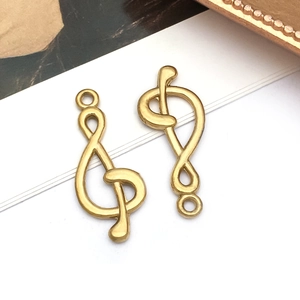 Detailed macro view of gold-plated treble clef music note pendants for DIY jewelry crafting