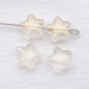 Macro shot of 8mm frosted star glass beads with gold glitter for DIY jewelry making