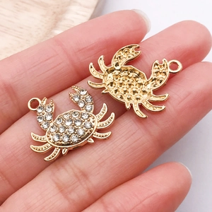 Macro shot of crab pendant charms featuring sparkling rhinestones and golden metal back