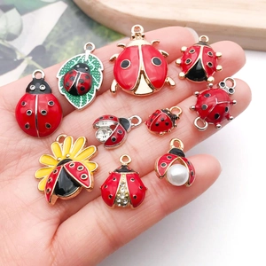 Breloques coccinelles en émail coloré pour bijoux DIY présentées dans la main