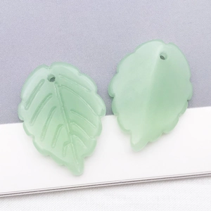 Detail showing two frosted light green glass strawberry leaf pendants with vein texture