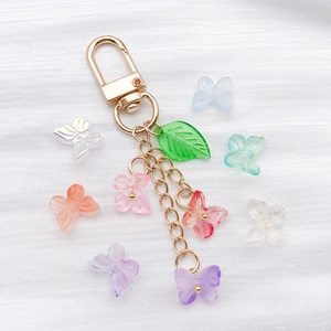 Gros plan de perles papillon en verre et pendentif feuille sur chaînes dorées