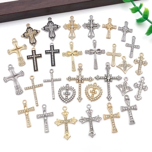 Flat lay of multiple vintage cross pendants in gold and silver with rhinestones