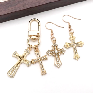 Detail view of gold-plated alloy cross pendant and earrings set with inlaid rhinestones