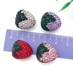 Dettaglio di ciondoli a fragola da 2cm con strass lucidi e un righello viola graduato