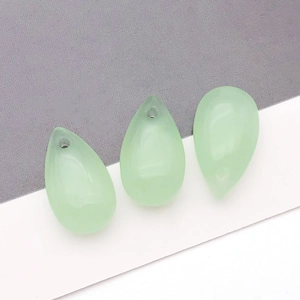 Close-up of three light green teardrop glass beads with top-drilled holes for DIY jewelry