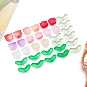 Macro detail of gradient glass tulip petals and green leaf beads for DIY jewelry making