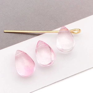 Vue macro de perles en cristal rose dégradé et détail de la tige métallique dorée