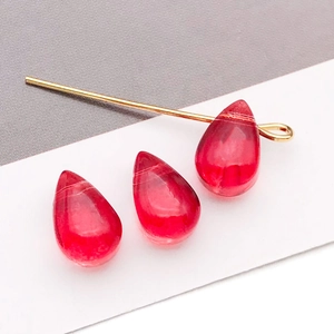 Détail macro de perles en verre goutte rouge et épingle dorée pour bijoux DIY