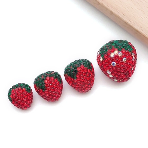 Detailed macro view of four strawberry shaped crystal pendants with red and green rhinestones