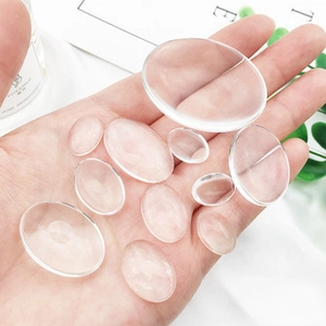 Clear oval glass cabochons held in hand showing multiple sizes for DIY jewelry making