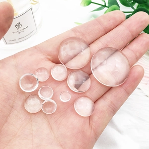 Clear glass dome cabochons for DIY crafts shown in hand for size comparison