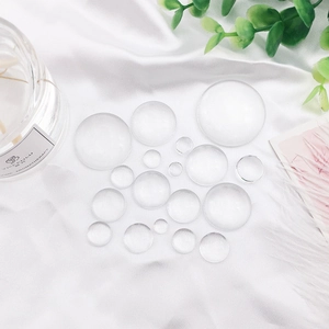 Transparent glass dome cabochons for DIY jewelry and keychains on white silk background