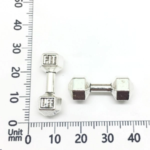 Primer plano de un dije de mancuerna de 20 mm con grabado Fit Life sobre escala mm