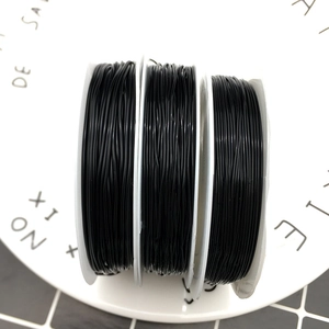 Three rolls of black elastic cord for DIY jewelry making displayed on a white plate