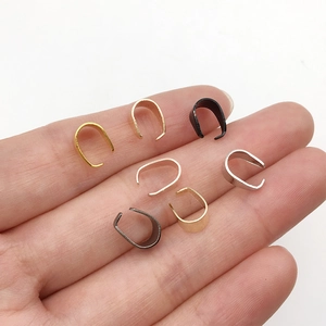 Bélières de bijoux multicolores présentées dans la paume pour l'échelle de taille