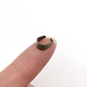 Vue macro de petites attaches en bronze vintage pour bijoux DIY posées sur un bout de doigt