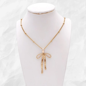 Collier avec pendentif nœud doré et chaîne perlée sur un buste de bijoux professionnel