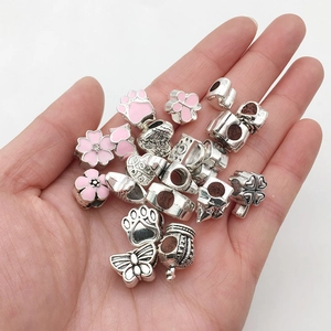 Macro shot of pink enamel cherry blossom and butterfly charms for DIY jewelry making