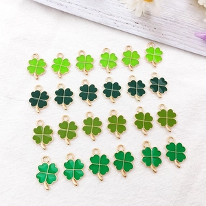 Macro shot of 24 green enamel four-leaf clover charms with gold metal frames for DIY