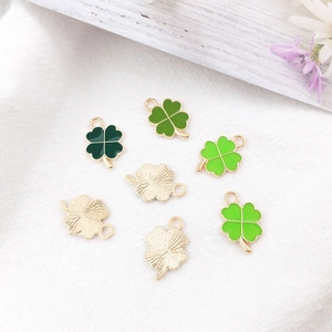 Detailed macro view showing green enamel clover charms with golden metal texture on back