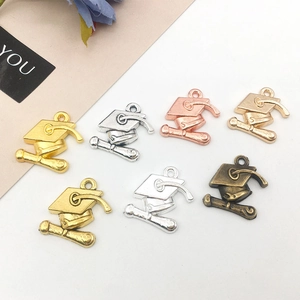 Macro detail of graduation cap charms in multiple metal finishes for DIY jewelry